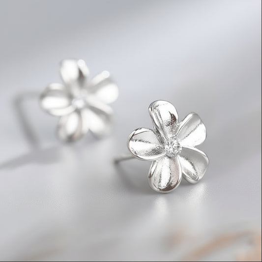Silver flower-shaped earring on a light gray background