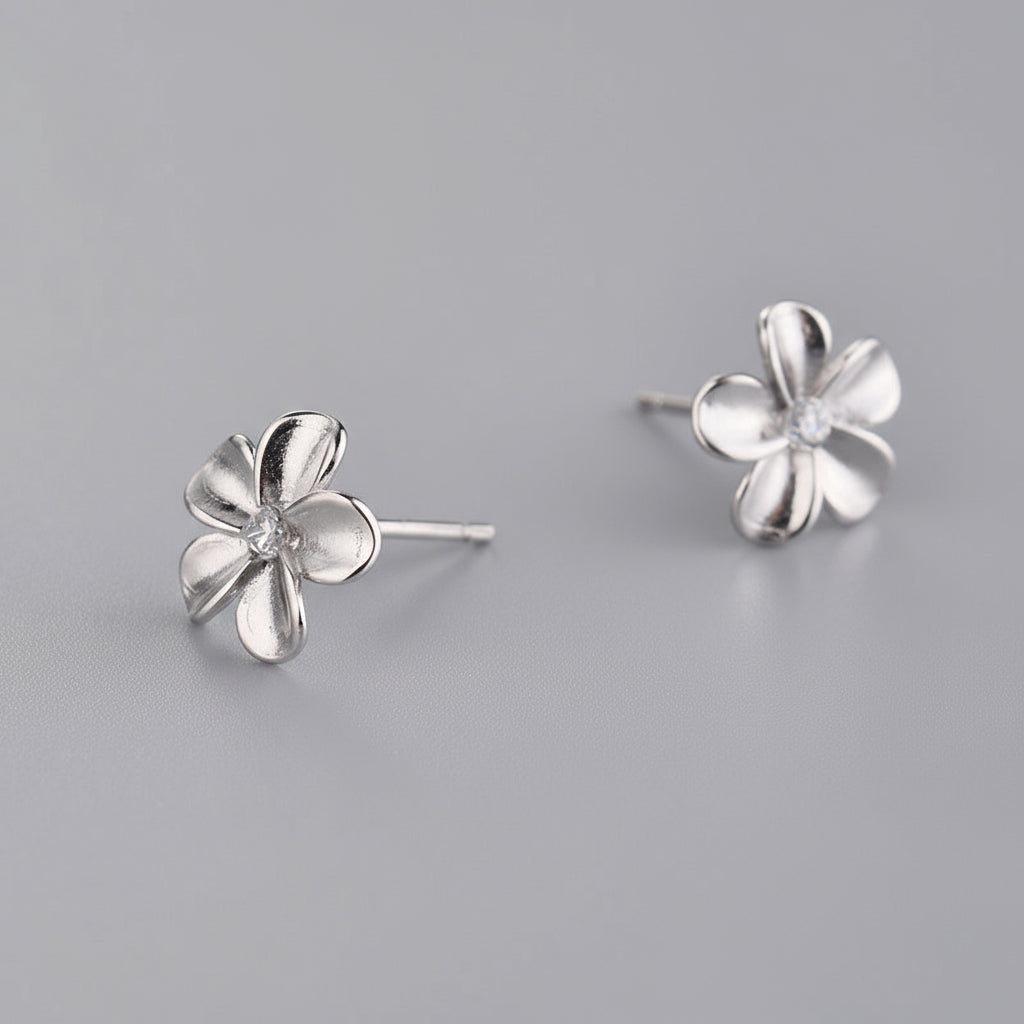 Silver flower-shaped earrings on a gray background