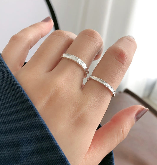 Hand wearing a silver ring on a blurred background