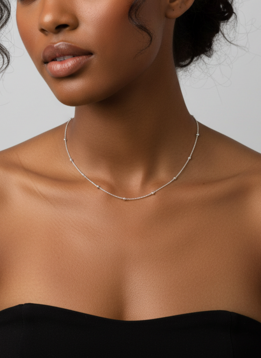 Silver necklace with small beads on a white background