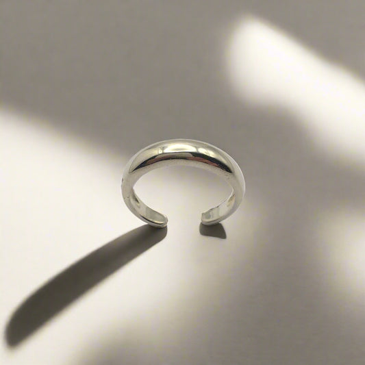 Silver ring on a reflective surface with soft lighting