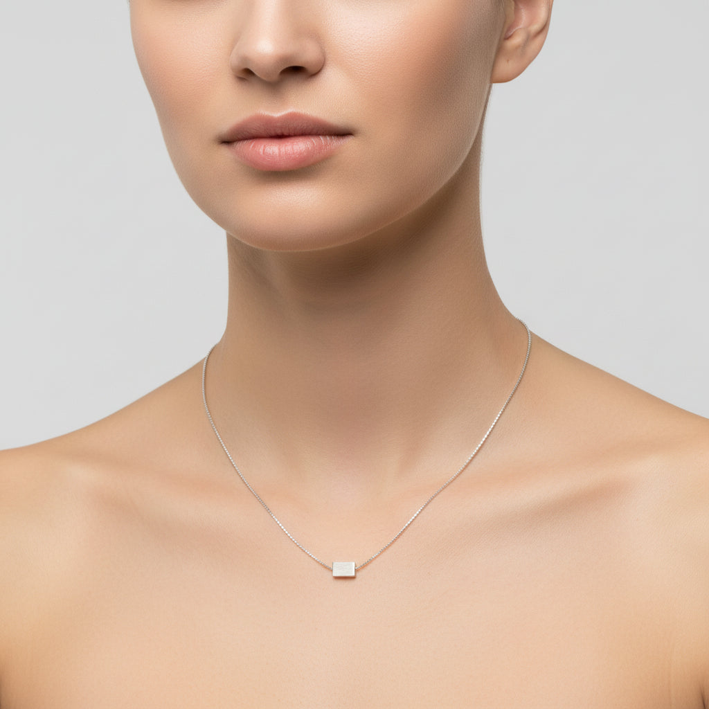Silver necklace with a square pendant on a white background