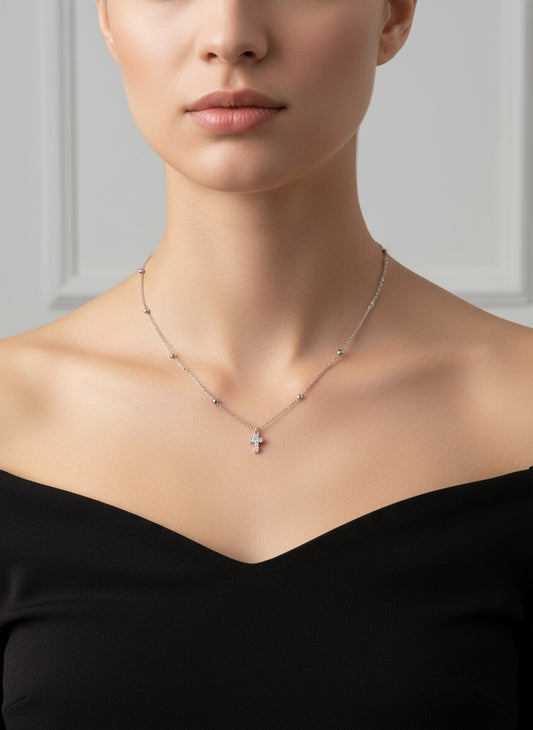 Silver necklace with a small cross pendant on a white background