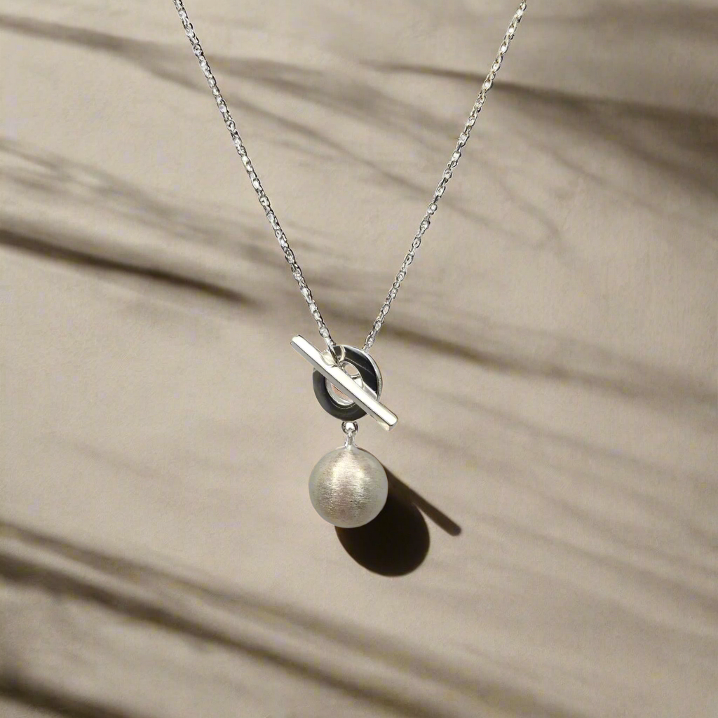 Necklace with a pendant featuring a pearl and black and silver design on a white background