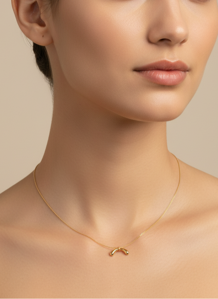 Gold necklace with a simple pendant on a white background