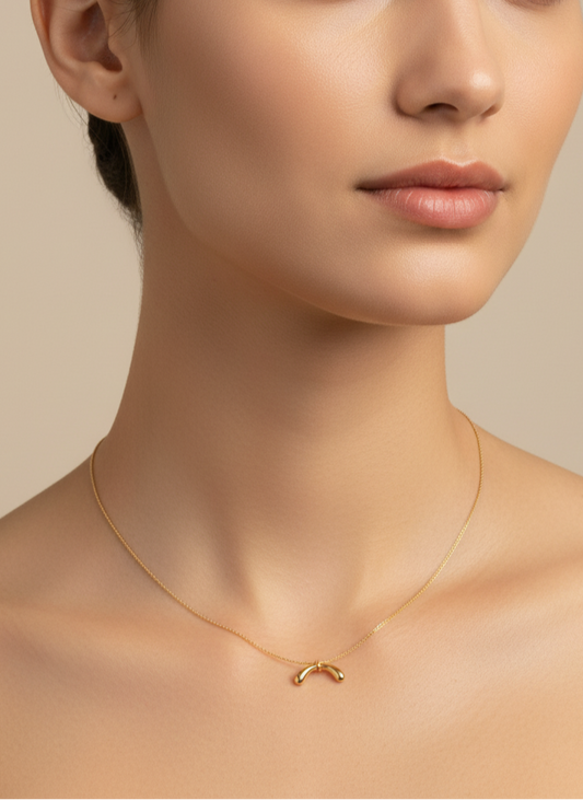 Gold necklace with a simple pendant on a white background