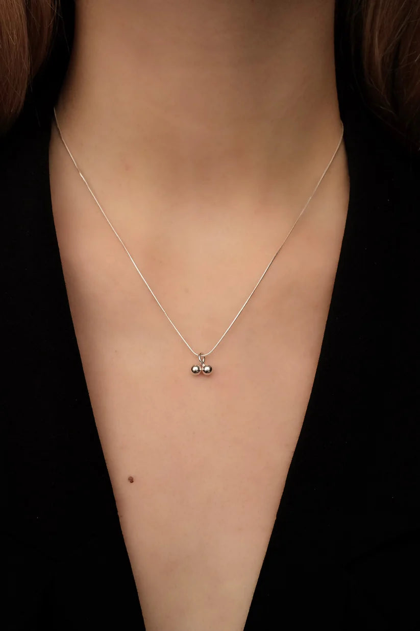 Necklace with a pendant on a person's neck against a black background