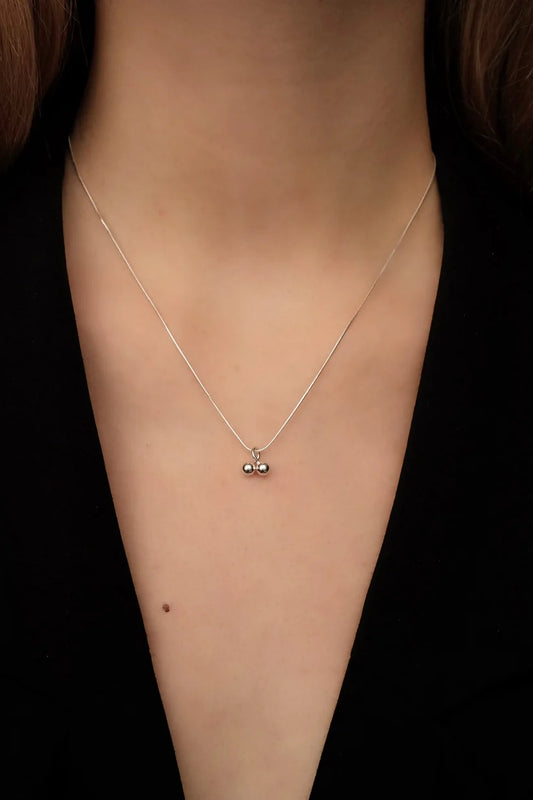 Necklace with a pendant on a person's neck against a black background