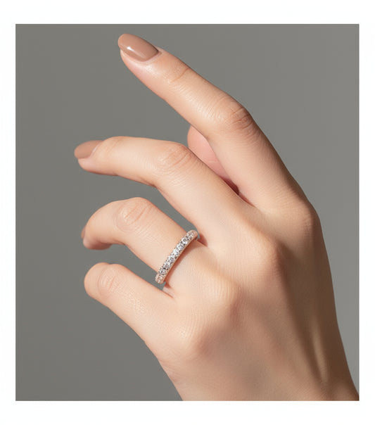 Close-up of a hand wearing a silver ring with a textured band against a neutral background