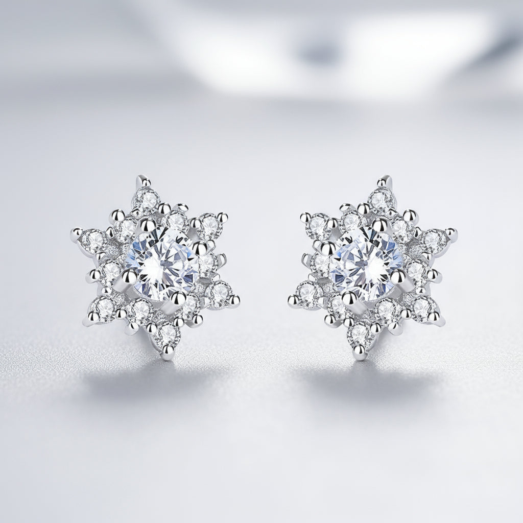 Pair of silver snowflake-shaped earrings with clear gemstones on a white background
