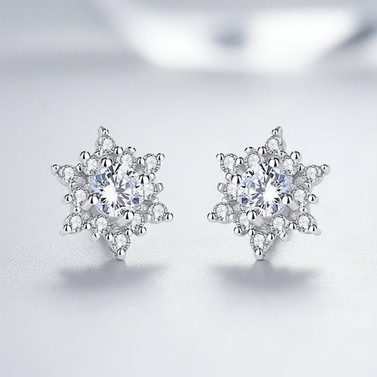 Pair of silver snowflake-shaped earrings with clear gemstones on a white background