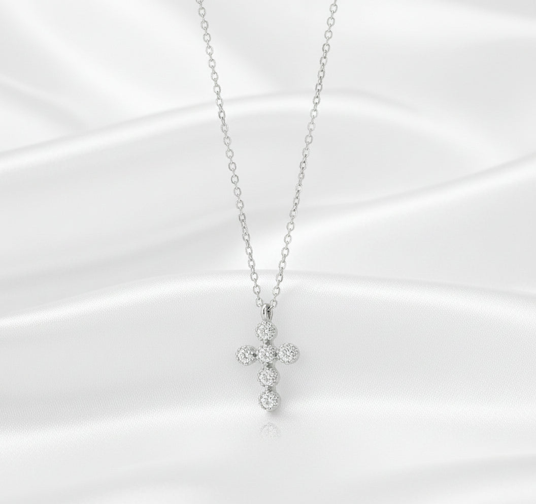 Silver cross necklace with clear stones on a black background