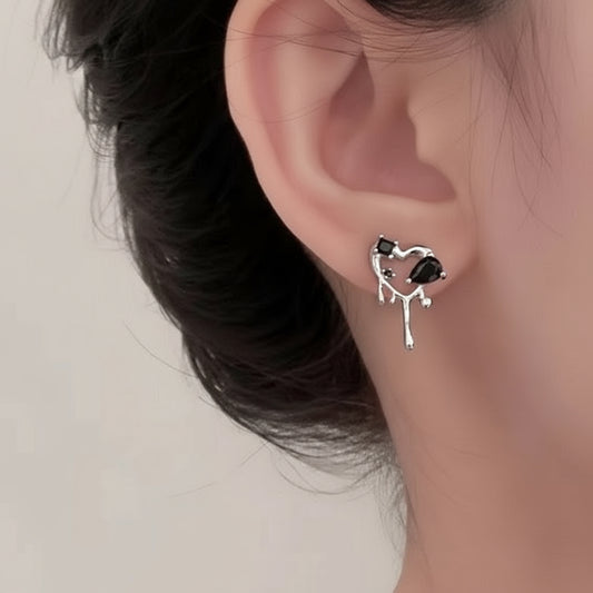 Close-up of an ear wearing a unique earring with a black gemstone on a plain background
