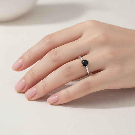 Silver ring with a heart-shaped black gemstone on a white background