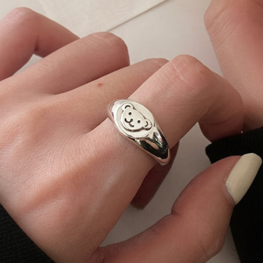 Two hands wearing silver rings on a light background