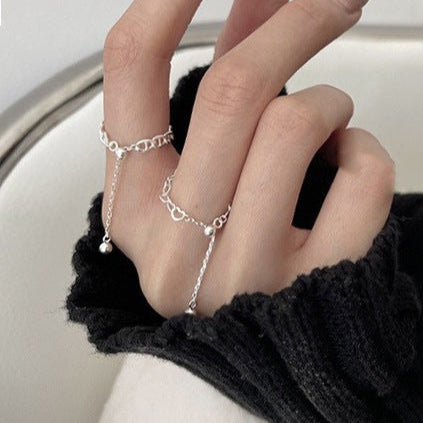 Close-up of a hand wearing multiple silver rings with a black sleeve.