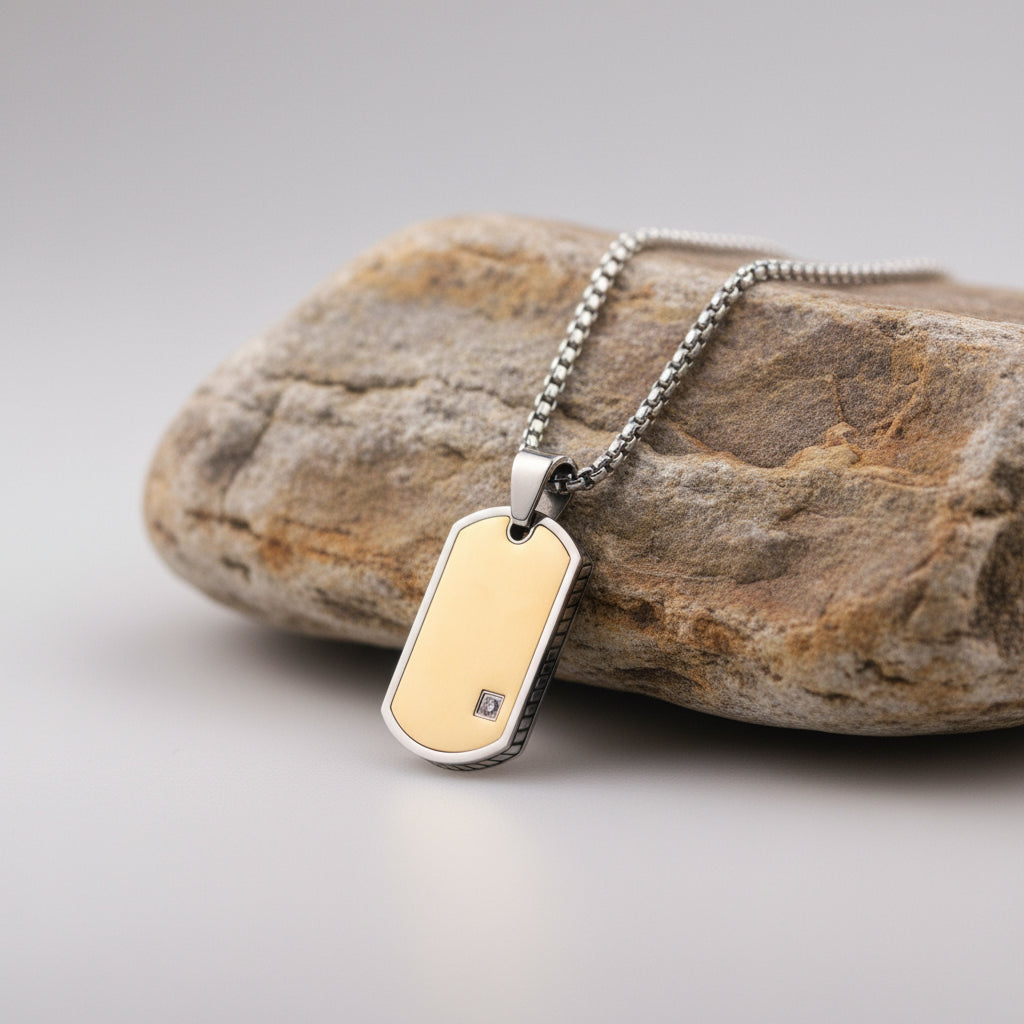 Gold dog tag pendant on a chain with a wooden block and gray surface in the background