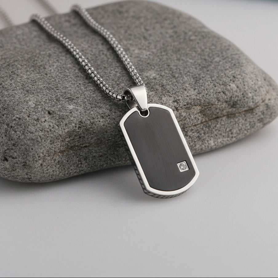 Silver dog tag necklace with a black finish on a wooden block