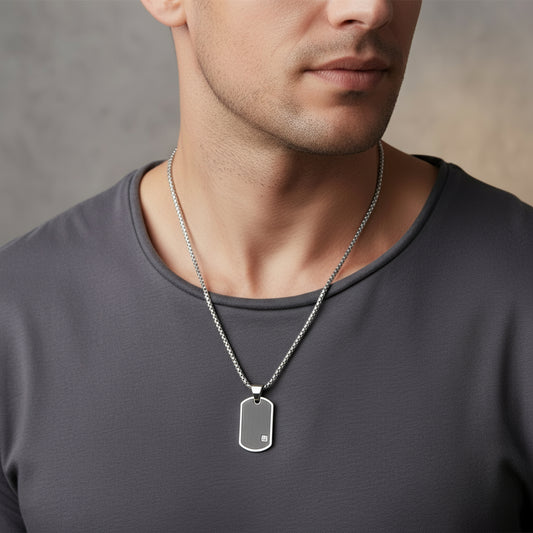 Dog tag necklace with black pendant on a stone surface