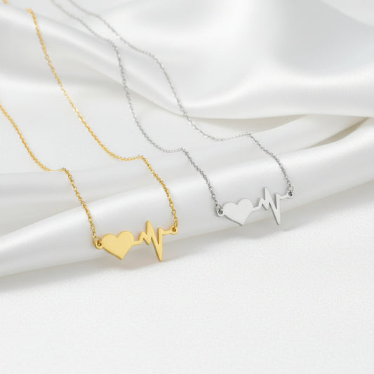 Gold necklace with a heart and heartbeat design on a white background