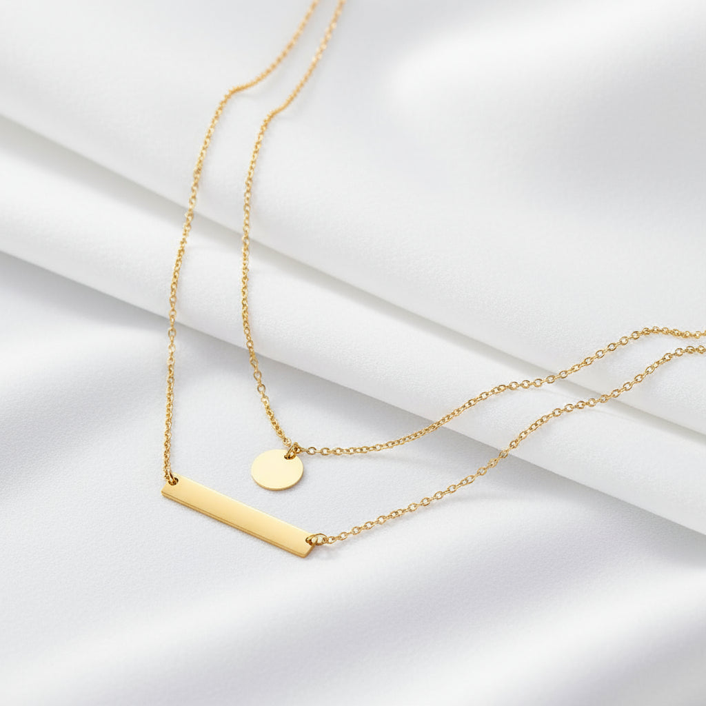 Gold necklace with two pendants on a dark gray background