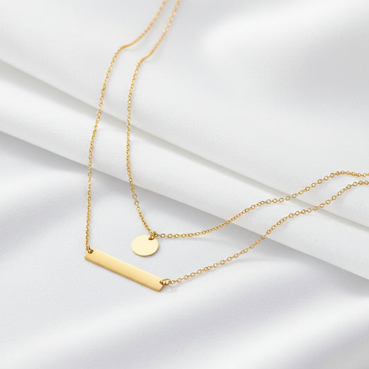 Gold necklace with two pendants on a dark gray background