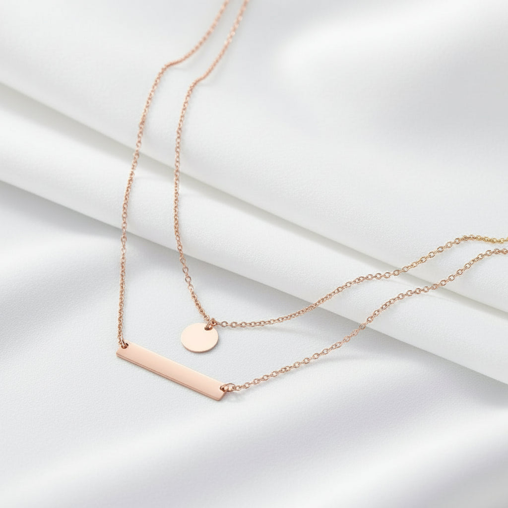 Gold necklace with a bar and round pendant on a white background