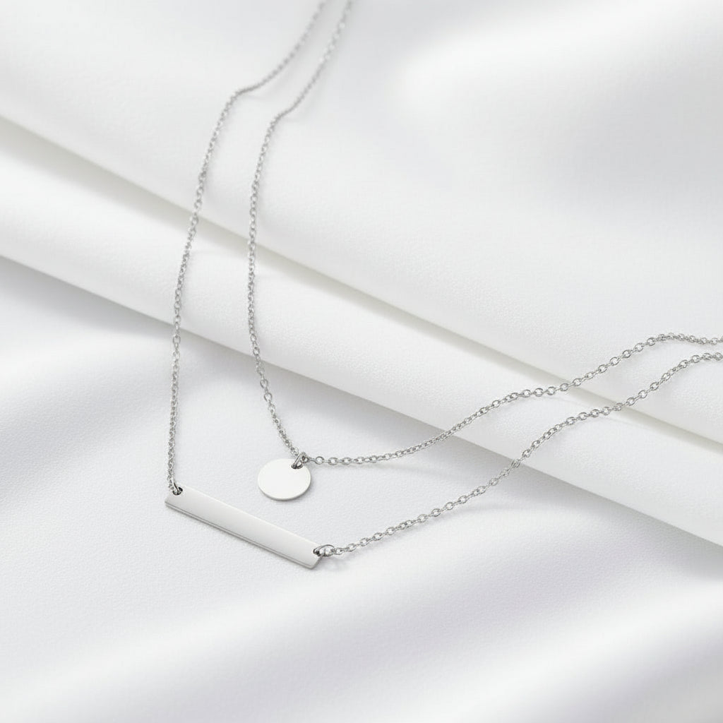 Gold necklace with a bar and round pendant on a white background