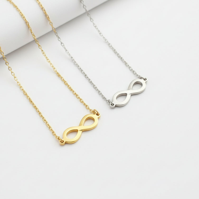 Three necklaces with infinity符号in gold, silver, and rose gold on a beige and white background