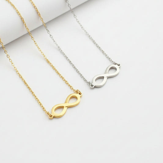 Three necklaces with infinity符号in gold, silver, and rose gold on a beige and white background