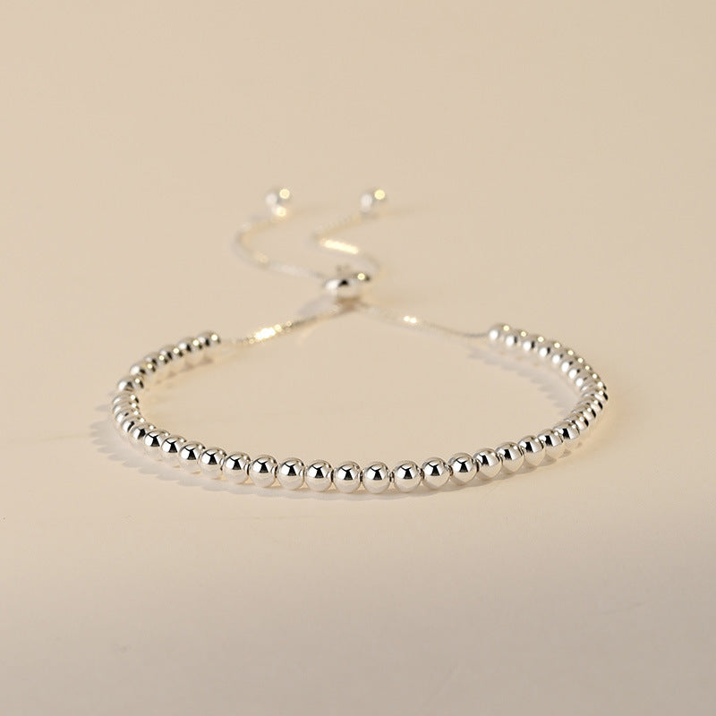 Silver beaded bracelet on a beige background