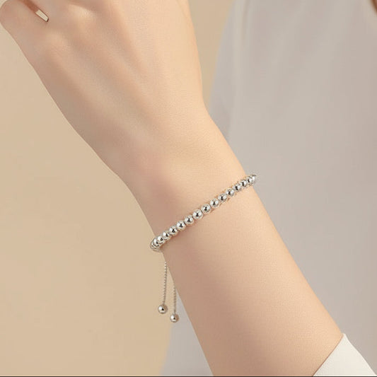Silver beaded bracelet on a beige background
