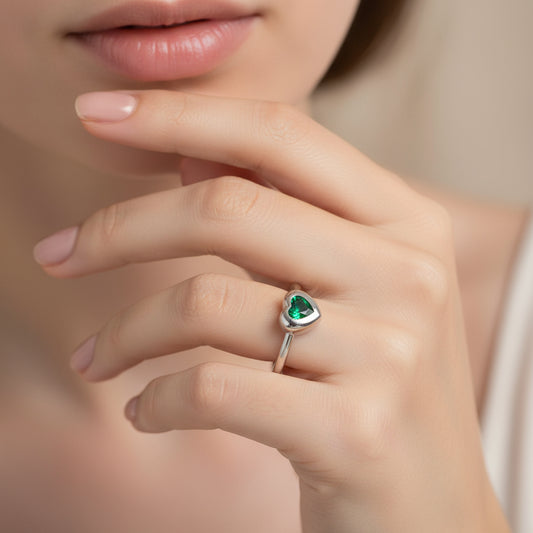 Silver ring with a heart-shaped green gemstone on a white background