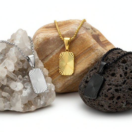 Three rectangular pendants on chains in silver, gold, and black on a white background