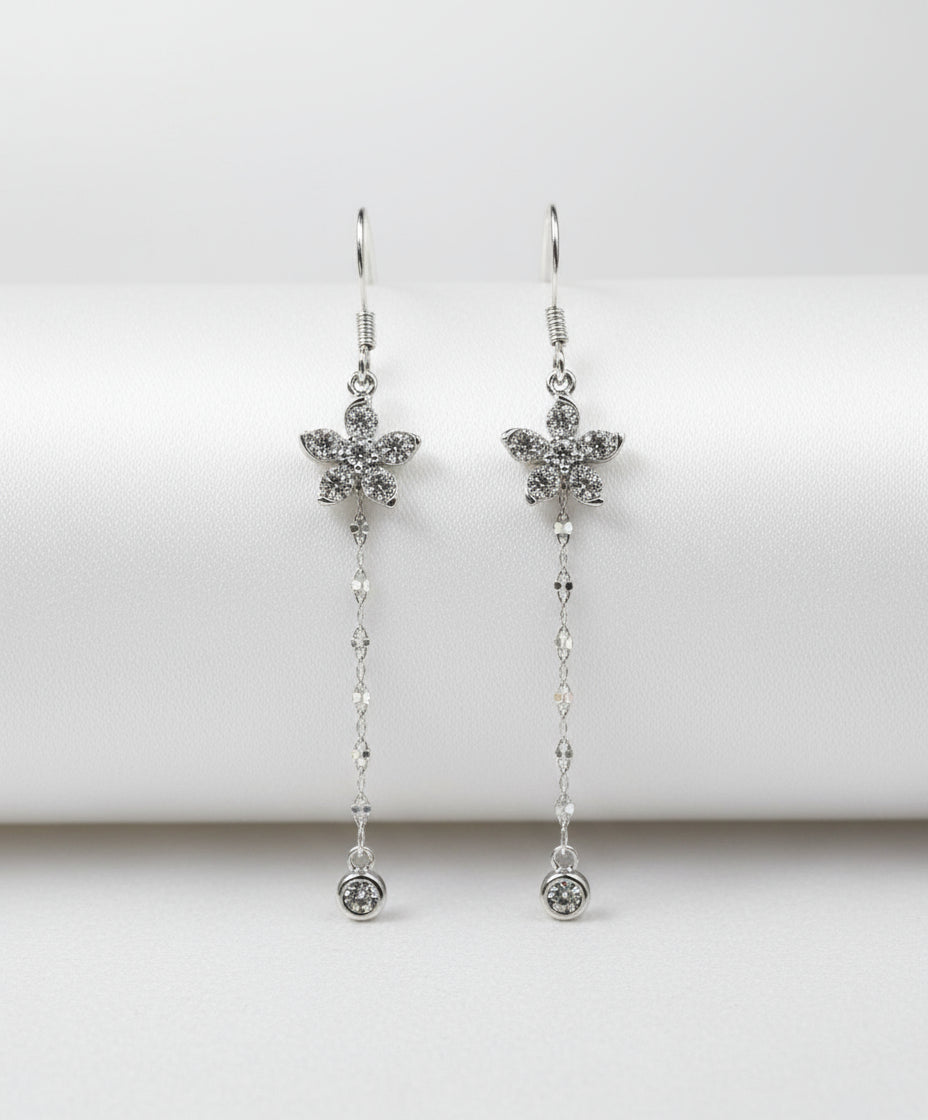 Silver flower earrings with chain details on a white background