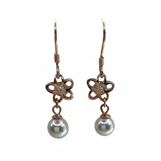 Pair of earrings with floral designs and pearl drops on a white background