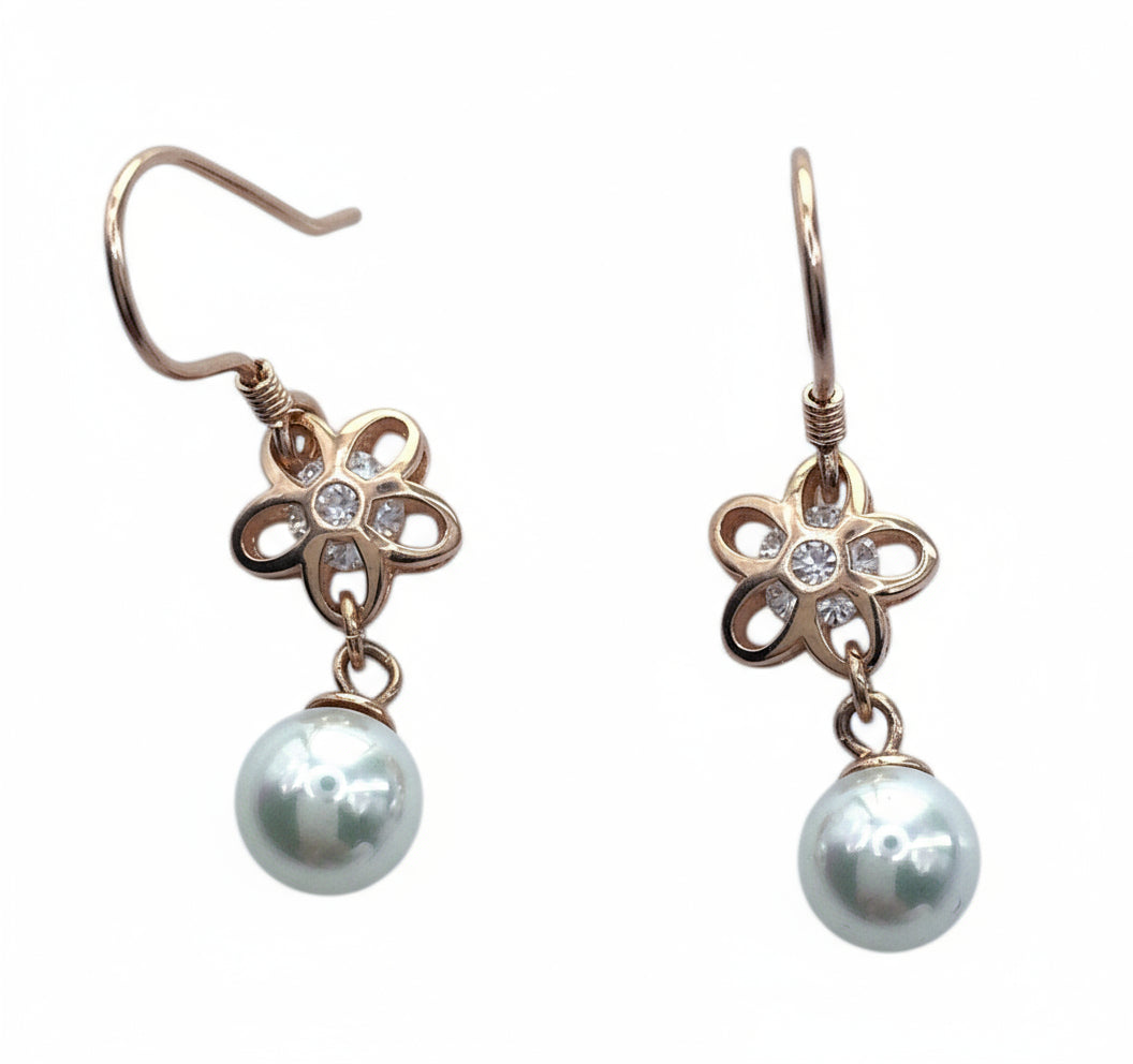 Pair of earrings with floral designs and pearl drops on a white background