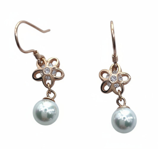 Pair of earrings with floral designs and pearl drops on a white background
