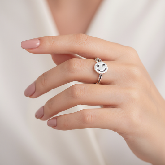 Silver open ring with a smiley face charm on a white background