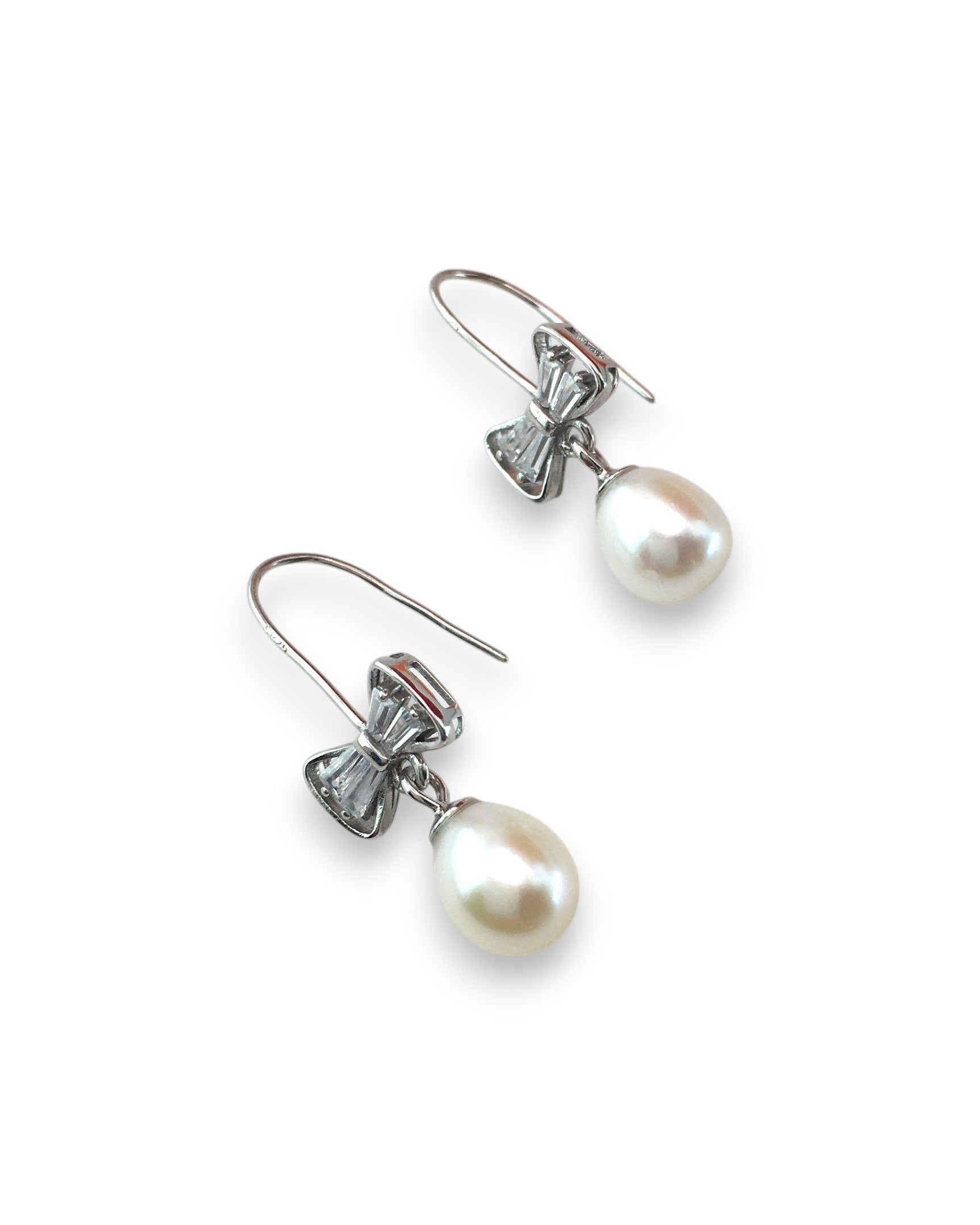 Pair of pearl earrings with bow-shaped clasps on a white background