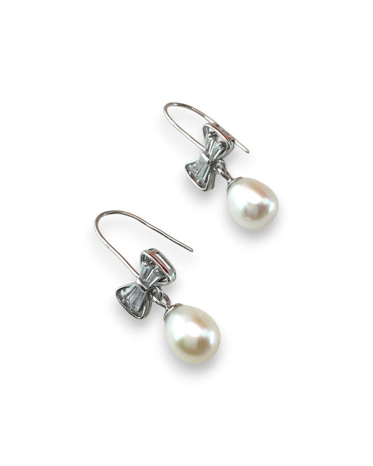 Pair of pearl earrings with bow-shaped clasps on a white background