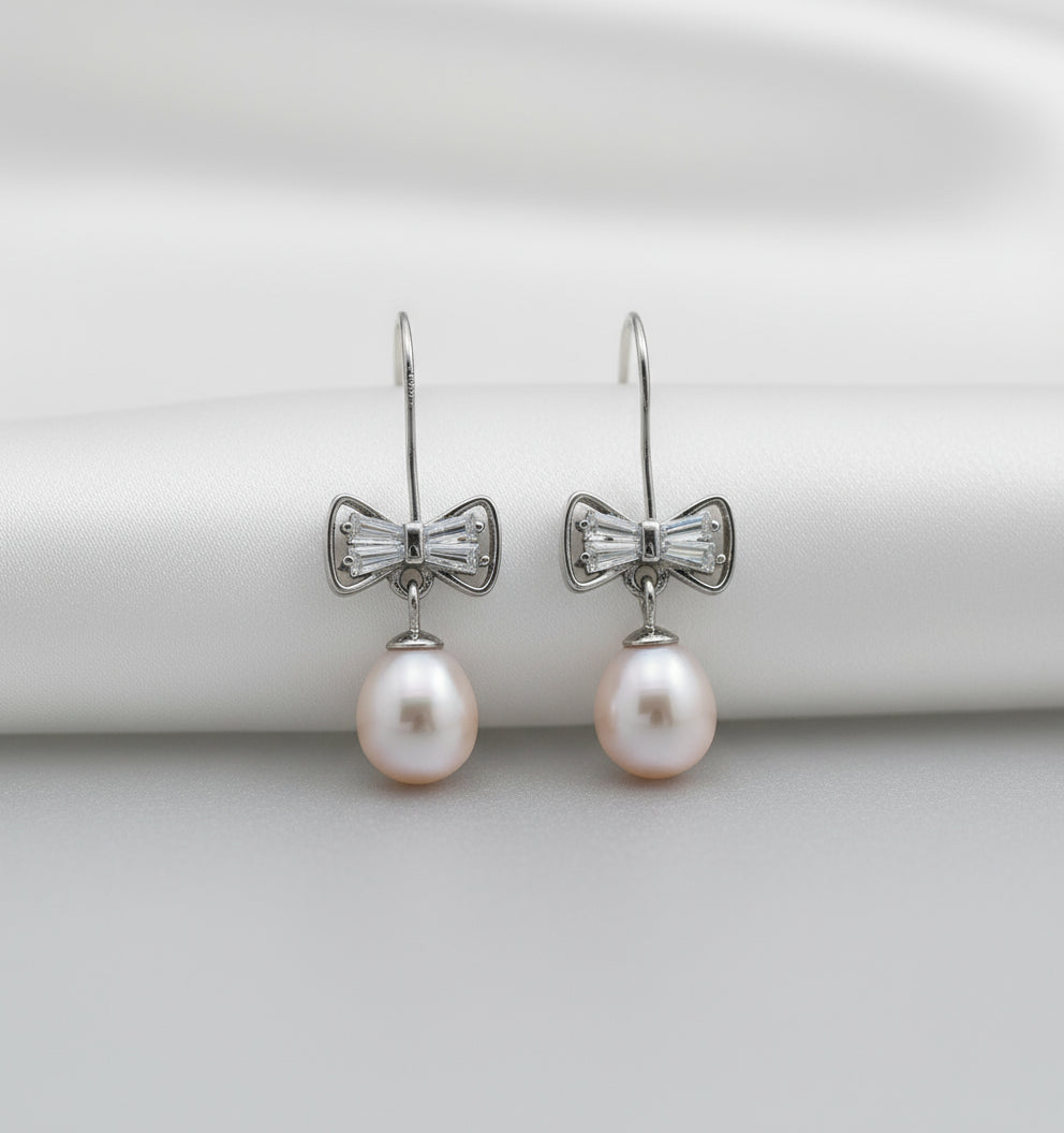 Pearl earrings with bow-shaped clasps on a white background