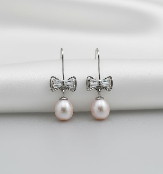 Pearl earrings with bow-shaped clasps on a white background
