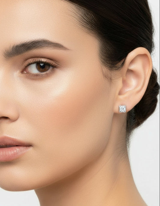 Pair of silver earrings with square gemstones on a white background
