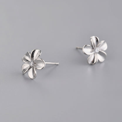 Silver flower-shaped earrings on a gray background