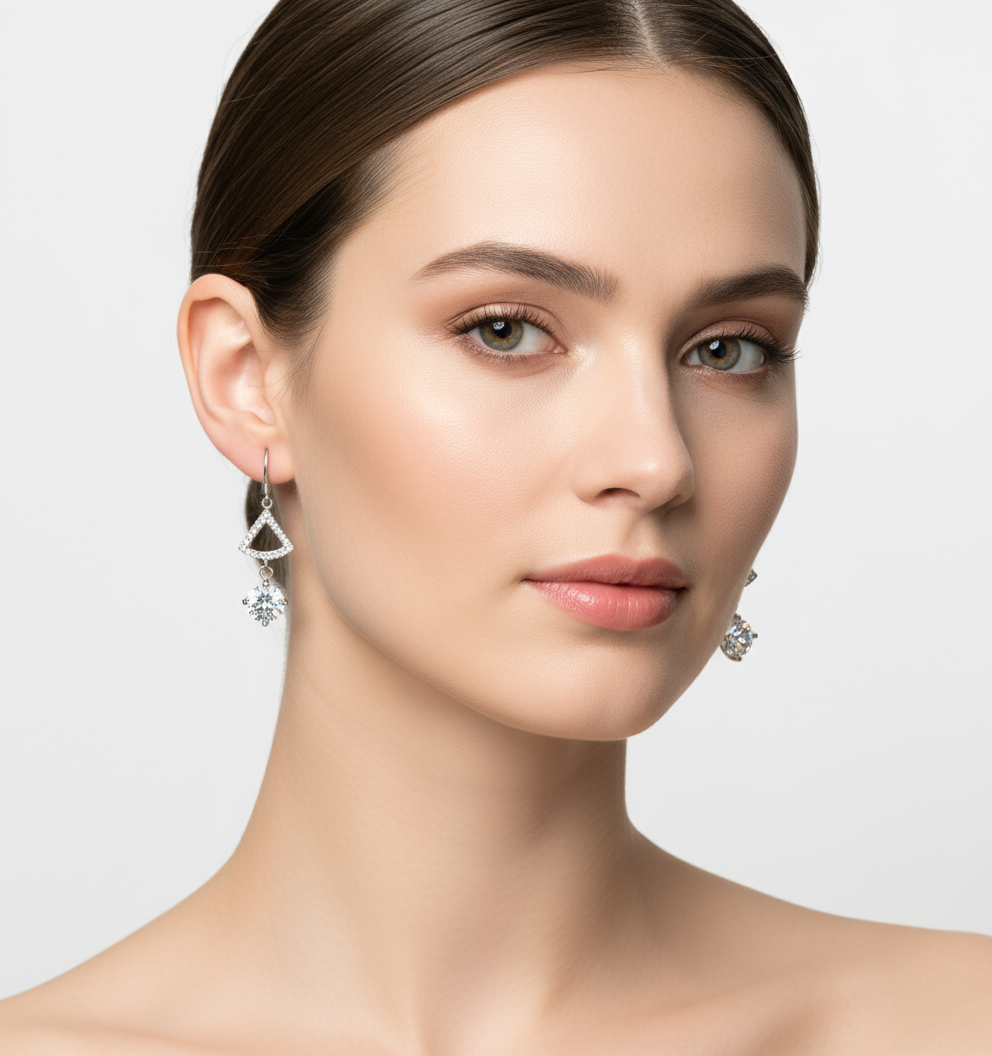 Pair of silver earrings with triangular designs and clear gemstones on a white background