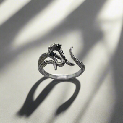 Silver ring with snake design on a light background