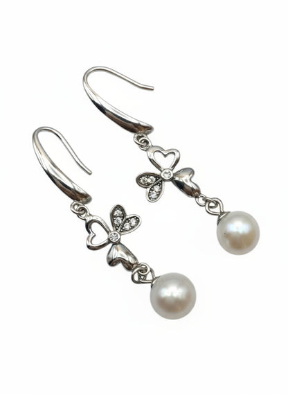 Pearl earrings with silver bow designs on a white background