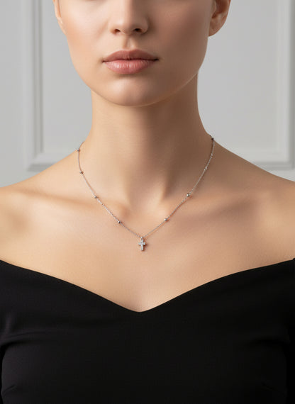 Silver necklace with a small cross pendant on a white background