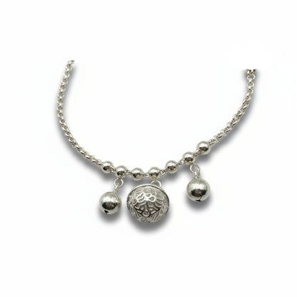 Silver bracelet with three charms on a white background